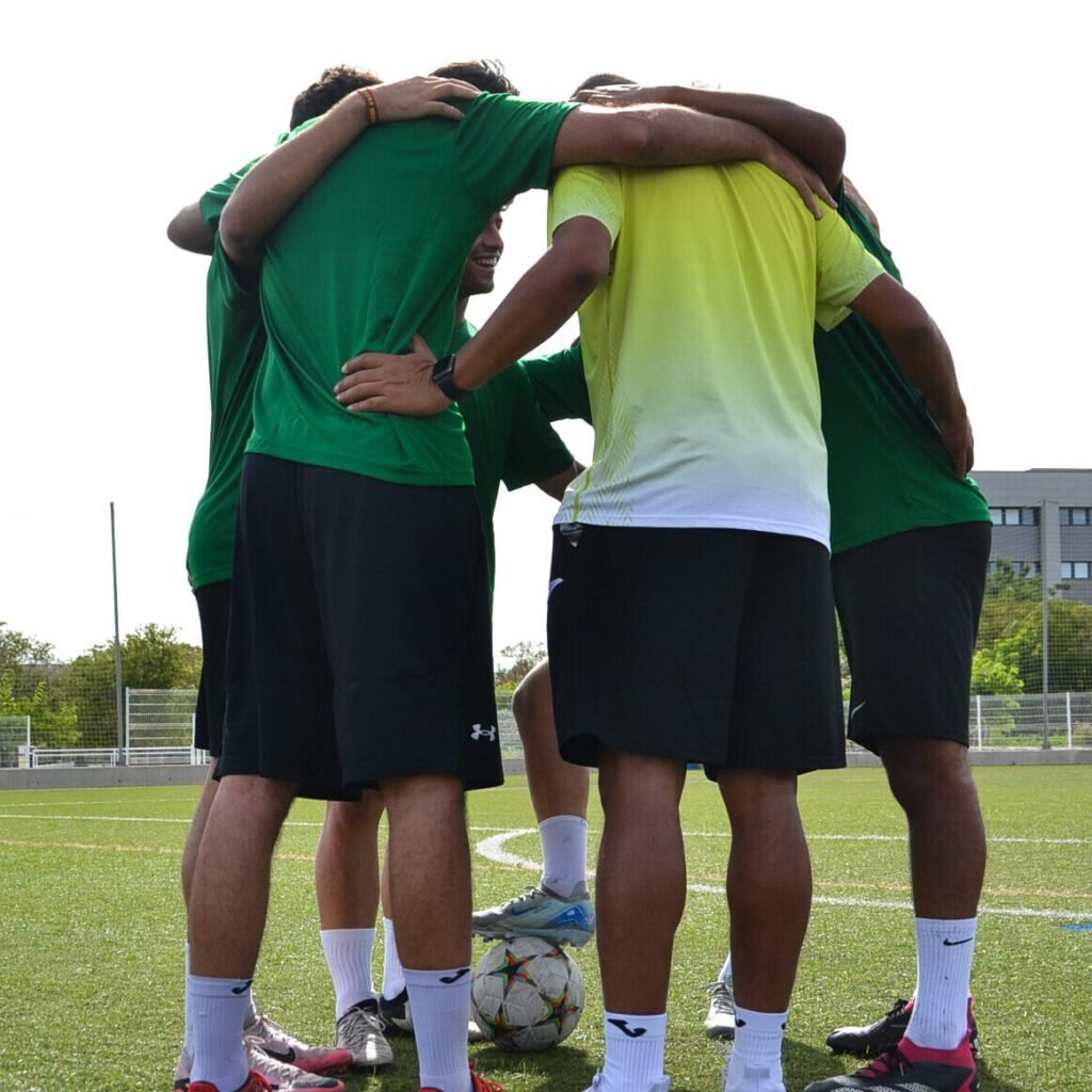 Grupo de futbolistas en círculo con los brazos unidos antes de un entrenamiento